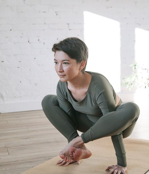 Woman in a calm yoga pose in a bright, serene room.